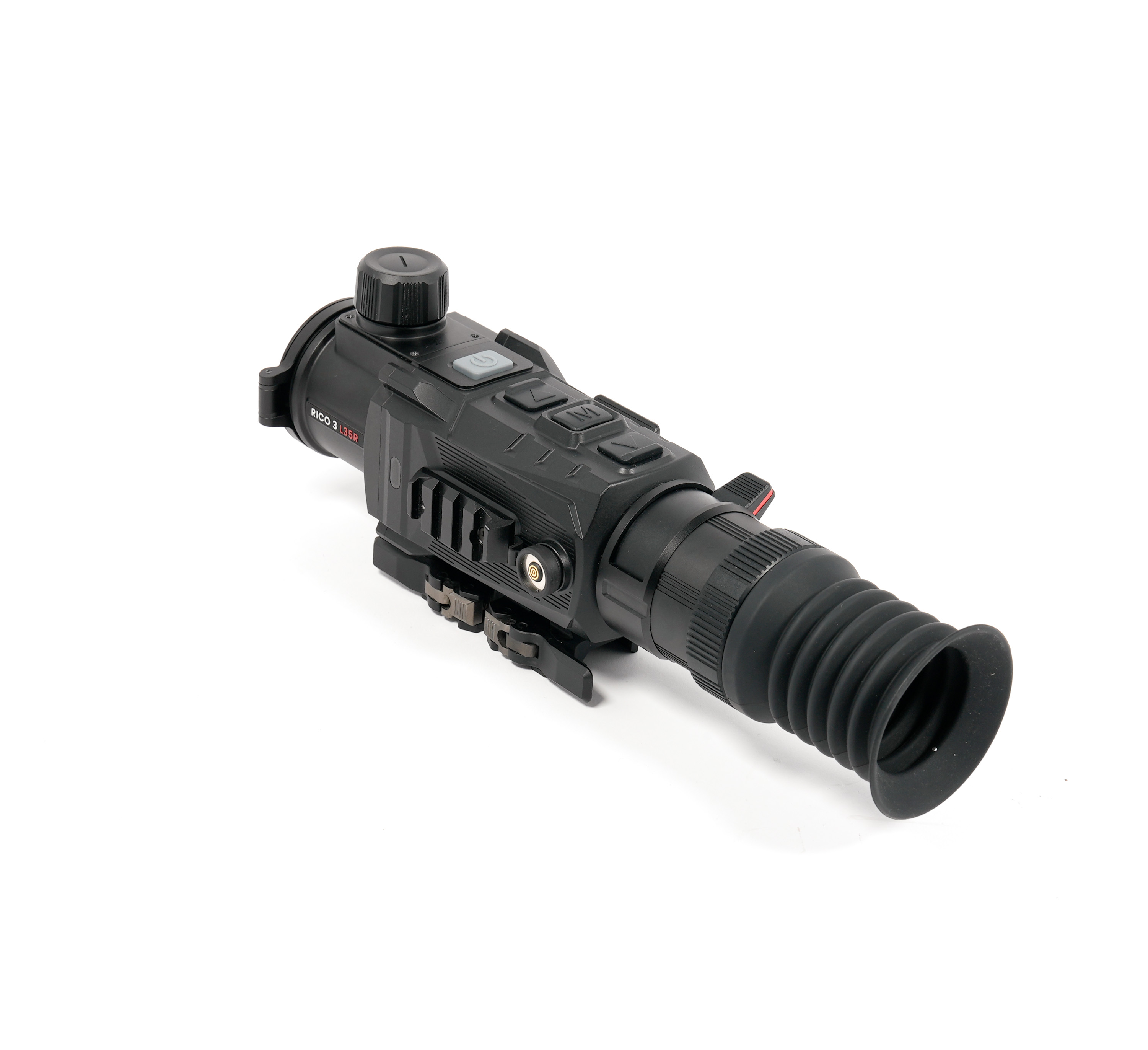 Close-up of a black optical sighting device with a large knurled adjustment dial and ribbed lens tube.