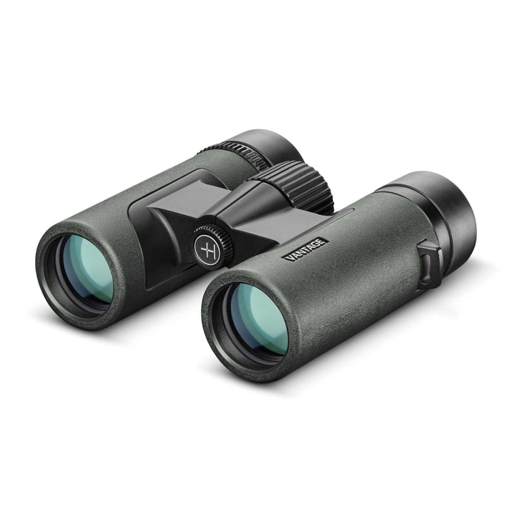 Compact green and black binoculars with a central hinge and textured focus wheel, angled for use on a bright surface.