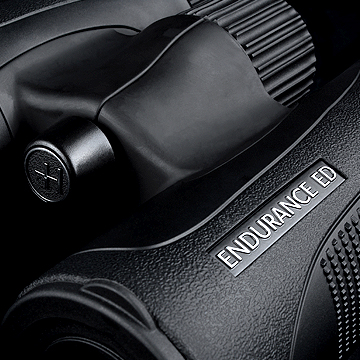 Close-up of a black camera body and lens with a textured grip and a metal badge reading ENDURANCE ED.